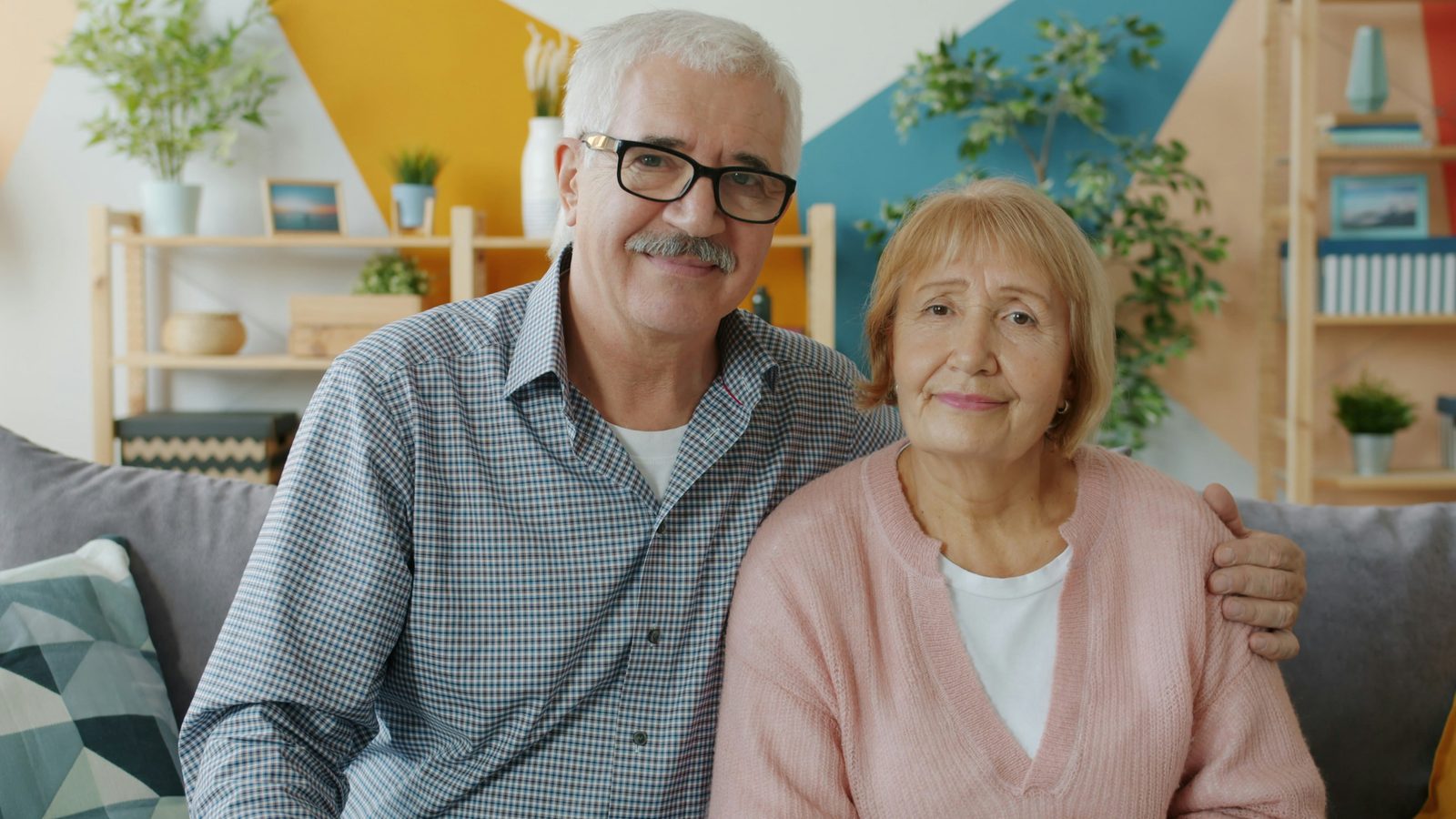 Elderly couple smiling while sitting on a couch